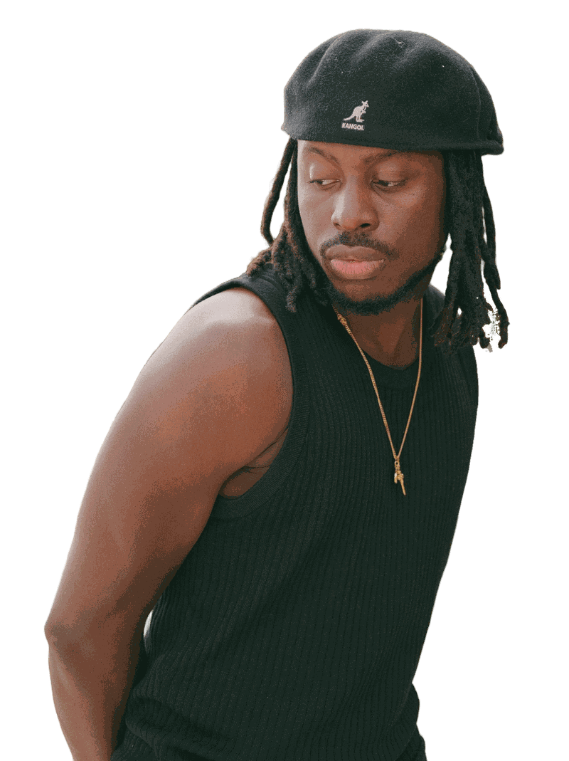 TMARO in a black Kangol beret and black tank top, looking over his shoulder